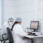 Dois cientistas analisam dados juntos em um computador dentro de um laboratório.