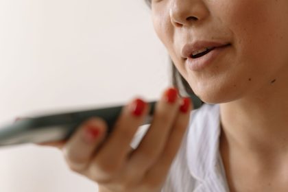 Mulher usa comando de voz no celular em um ambiente interno.