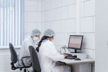 Dois cientistas analisam dados juntos em um computador dentro de um laboratório.