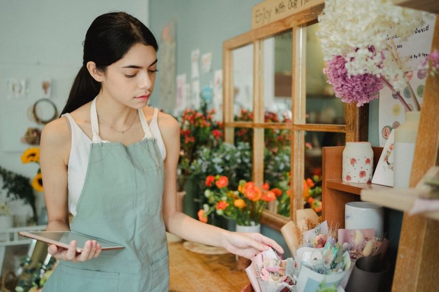 Microempreendedora confere um pedido em um tablet dentro de uma floricultura.