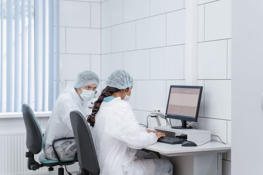 Dois cientistas analisam dados juntos em um computador dentro de um laboratório.