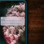 Smartphone exibindo uma notificação bancária sobre uma mesa de madeira.