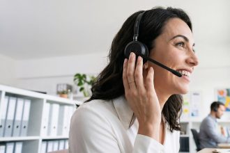 Mulher usando headset em um escritório durante atendimento ao cliente por telefone.