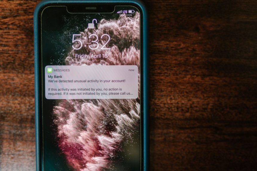 Smartphone exibindo uma notificação bancária sobre uma mesa de madeira.